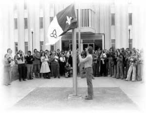 Michel Dupuis qui hisse le drapeau franco-ontarien devant l'Université de Sudbury le 25 septembre 1975. Source : Sudbury Star. Tiré du site Web de l'Encyclopédie du patrimoine culturel de l'Amérique française.